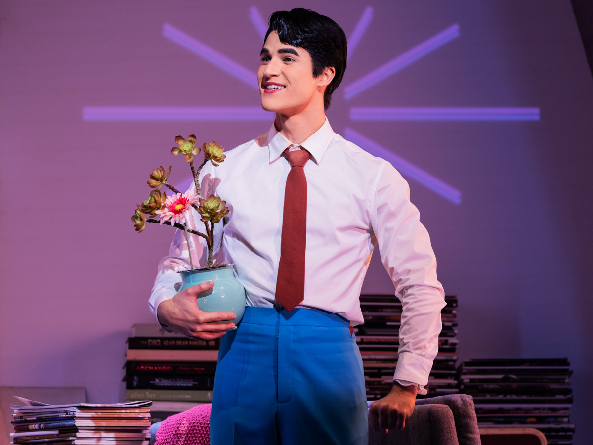 Helperbot Oliver stands smiling and holding a plant